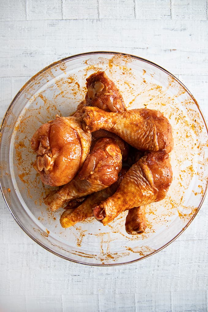chicken drumsticks tossed in a bowl of marinade
