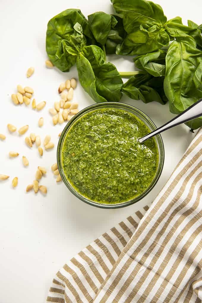 Pesto next to green basil and pine nuts