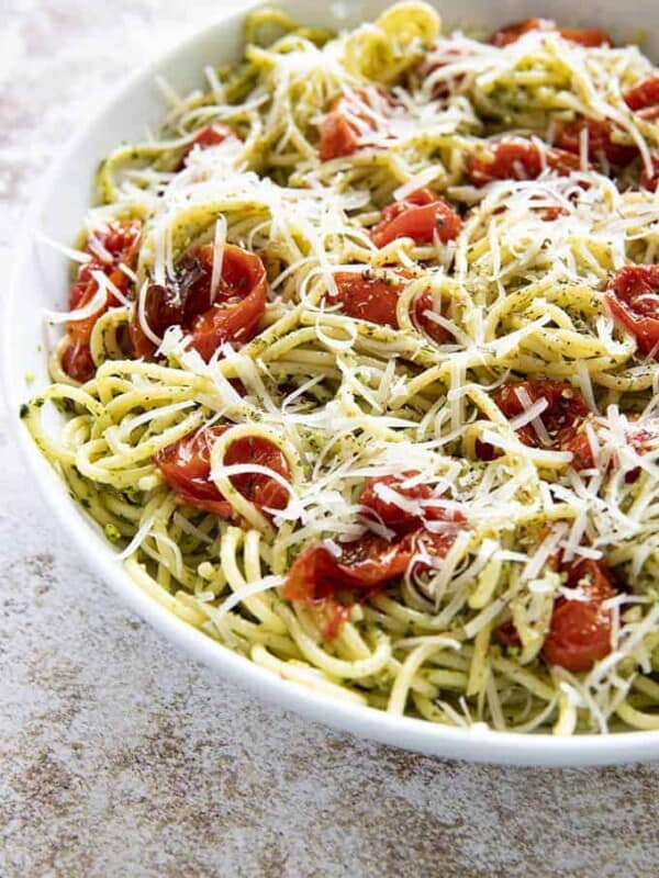 pesto pasta in a white bowl with tomatoes