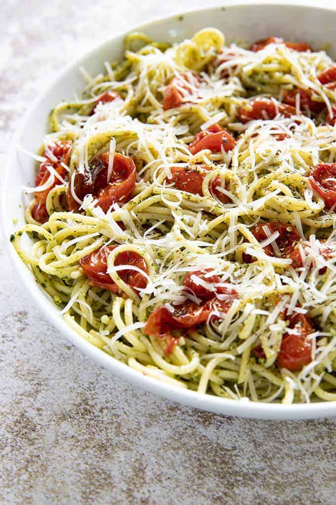 pesto pasta in a white bowl with tomatoes