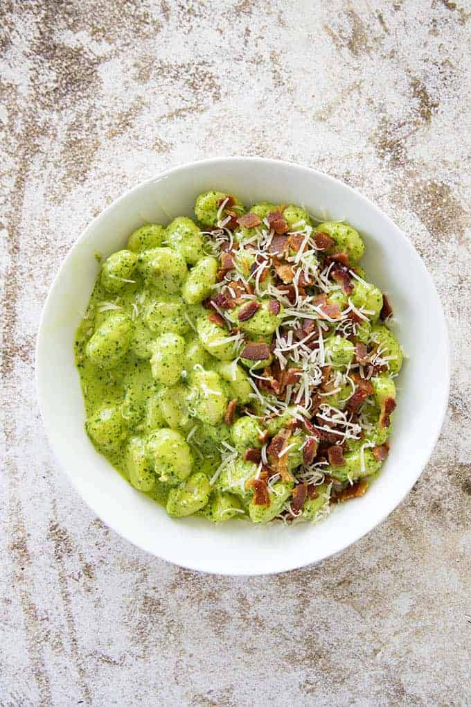 creamy pesto gnocchi in a bowl with bacon