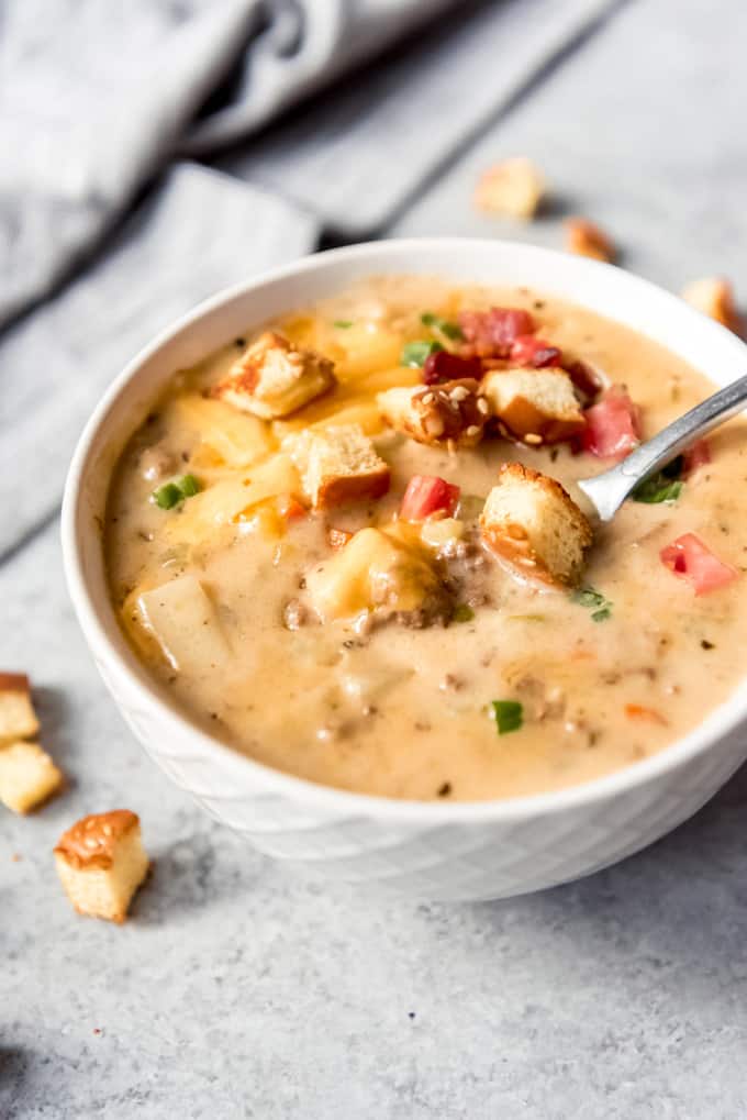 An image of a bowl of cheeseburger soup topped with garnishes.