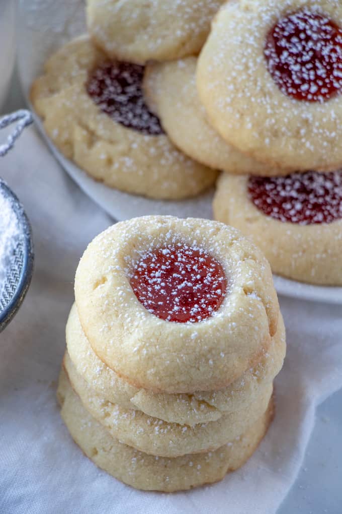 Thumbprint Cookies stacked on top of one another with plate of cookies in background