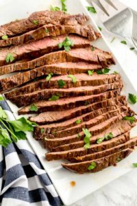 Slices of pan seared London broil on a white platter.