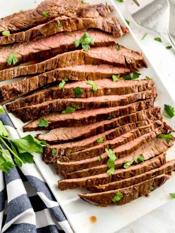 Slices of pan seared London broil on a white platter.