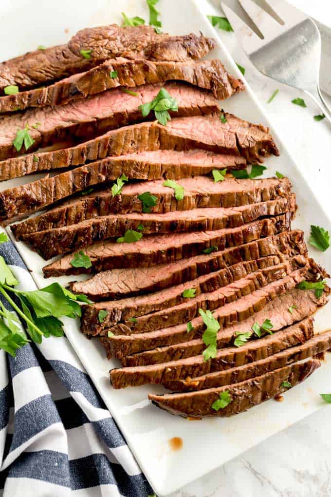 Slices of London broil on a white platter.