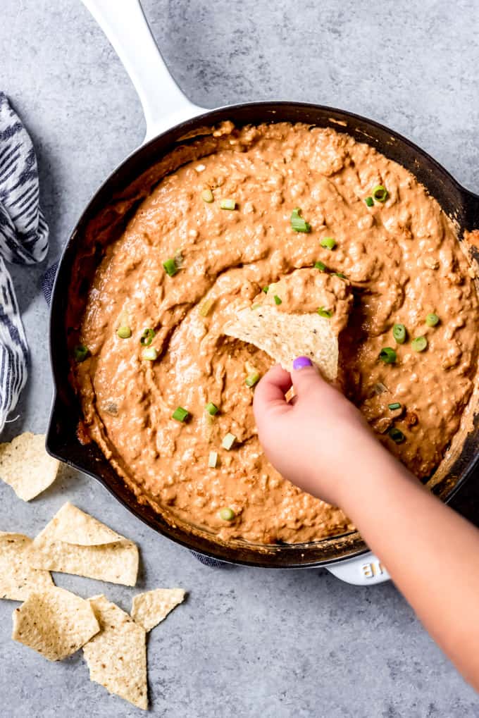 An image of a chip being used to scoop bean dip out of a pan.