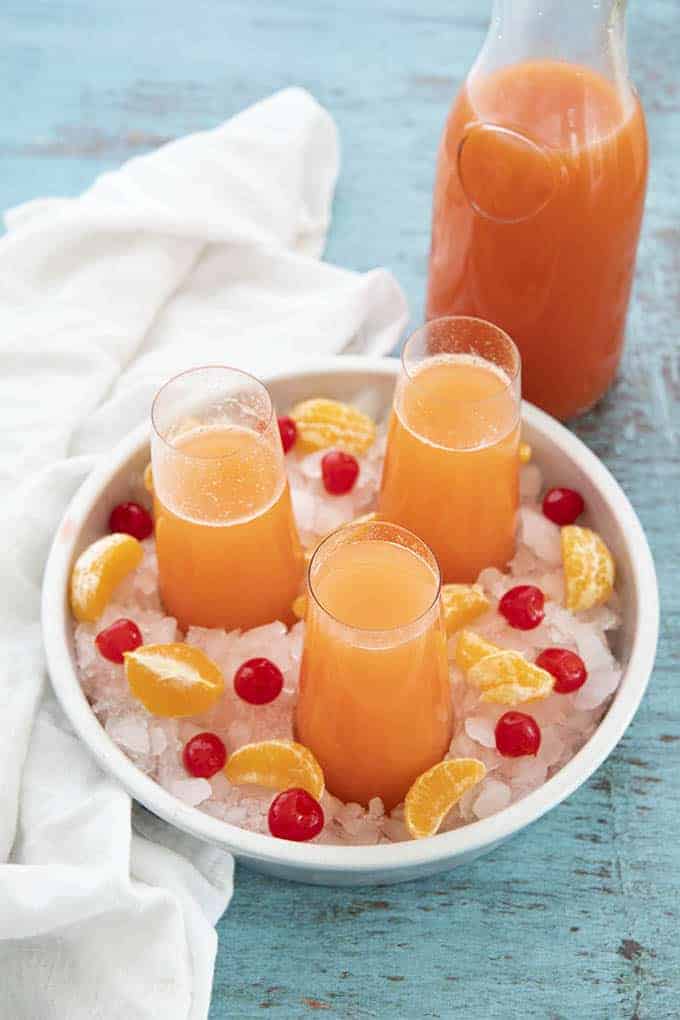 Mimosa punch in a glass on ice with oranges and cherries