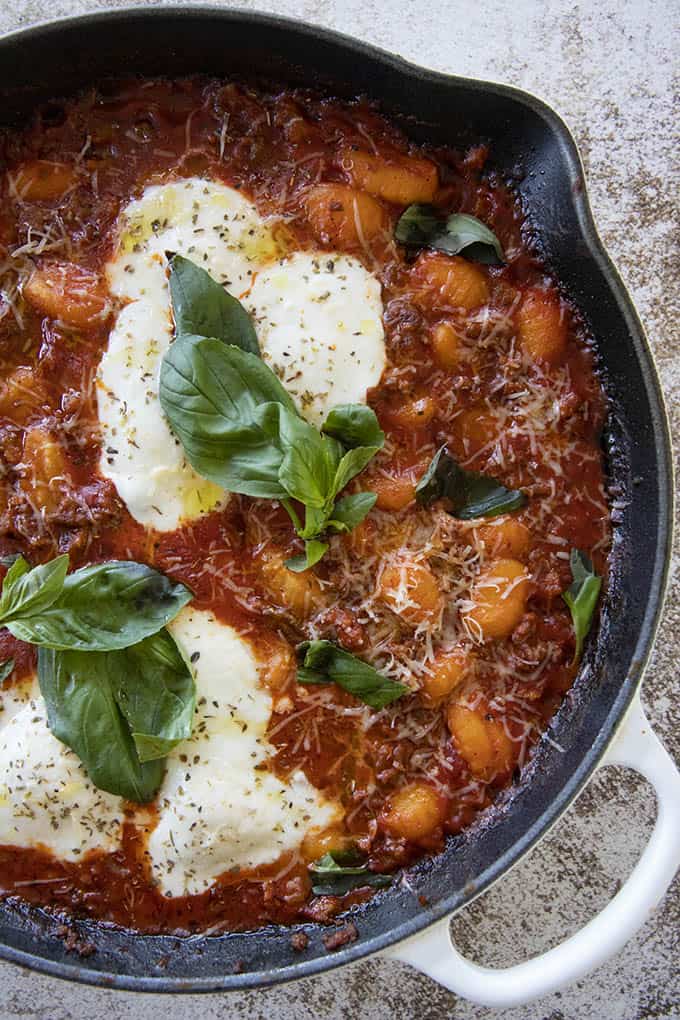 gnocchi in skillet topped with cheese and basil