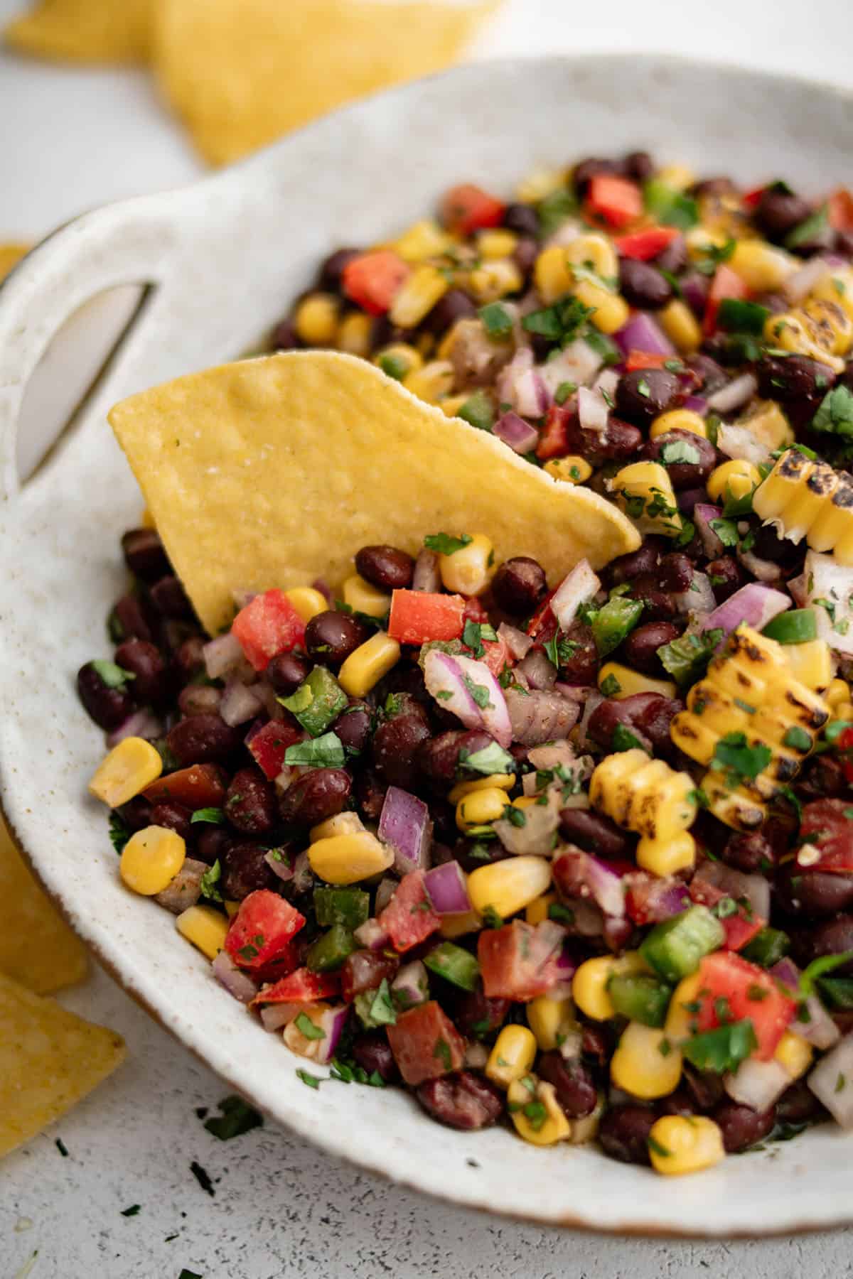 black bean salsa in a bowl with a tortilla chip dipped into it