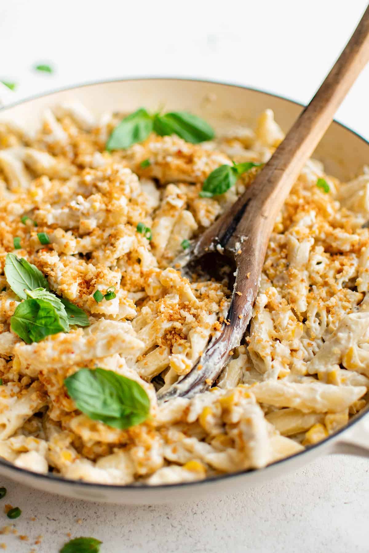 creamy corn pasta in a pan with a wooden spoon