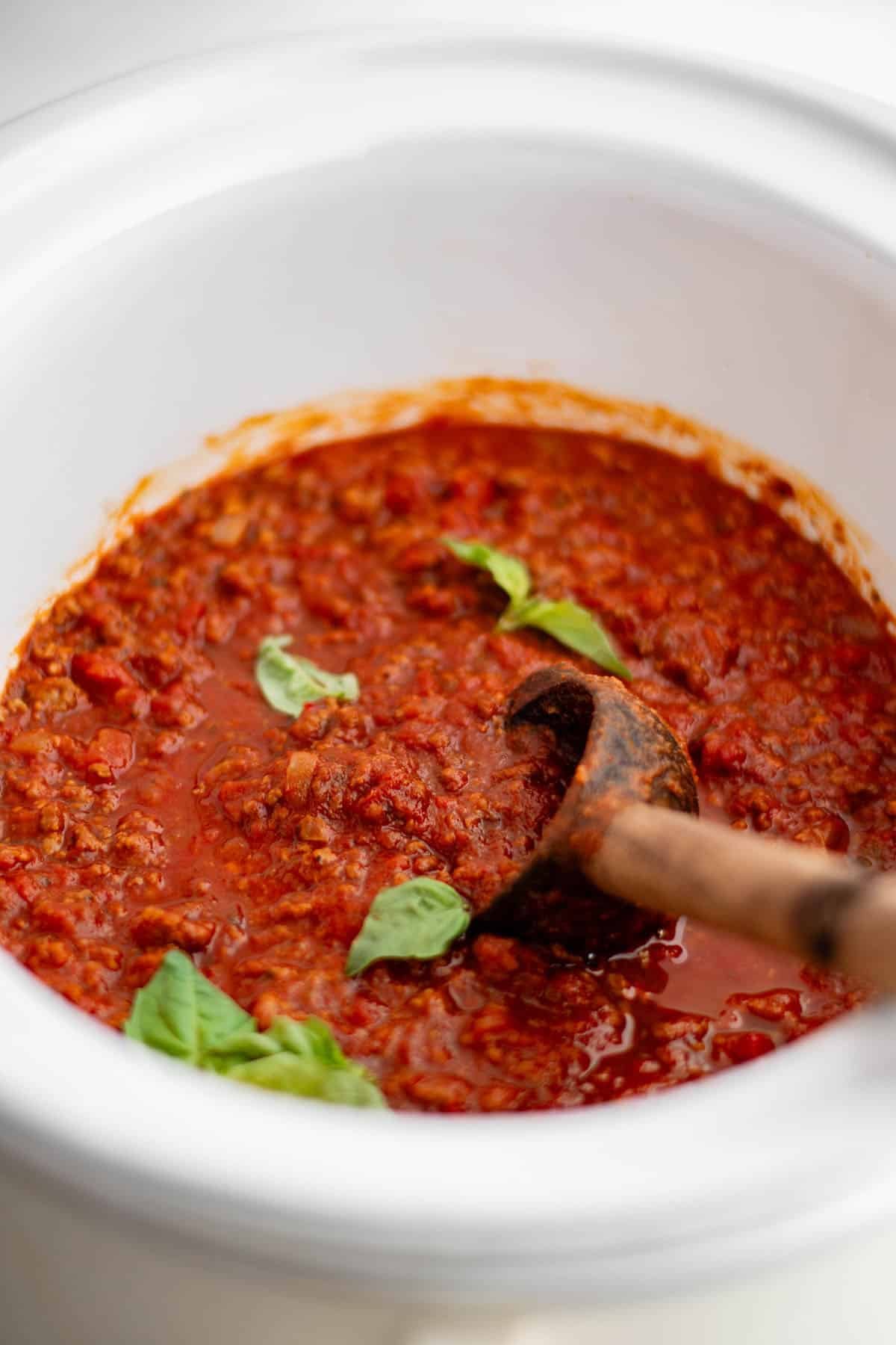 crockpot spaghetti sauce in a crockpot and garnished with fresh basil