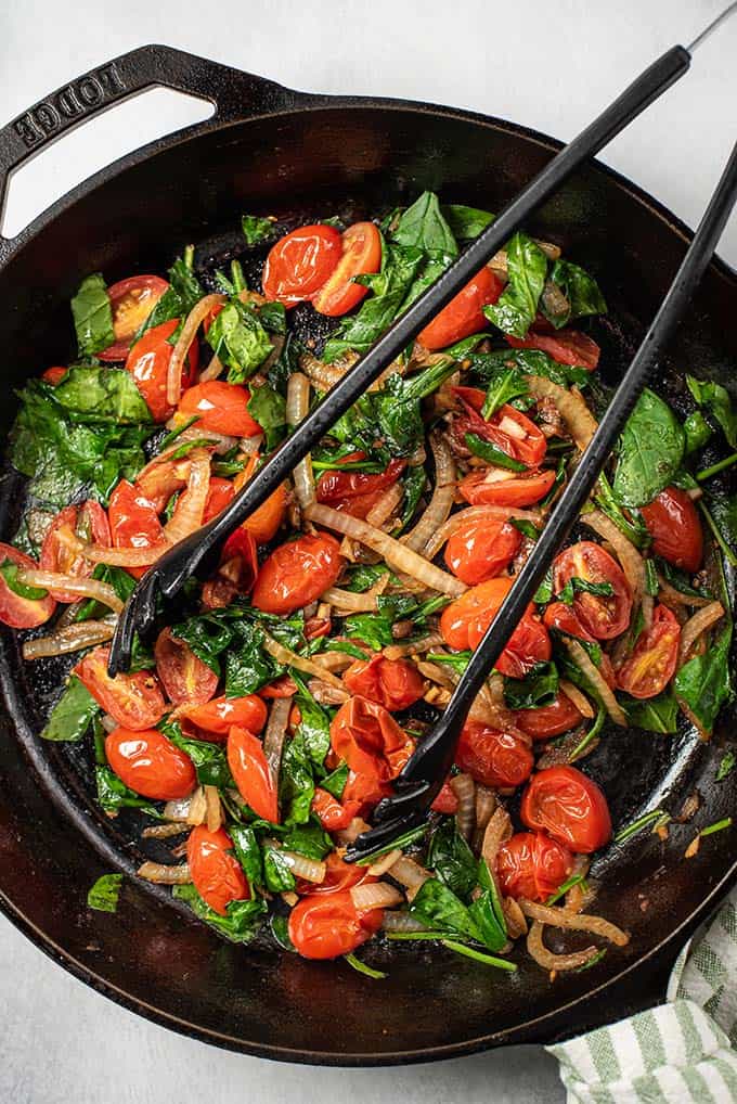 cherry tomatoes and spinach cooked in a skillet