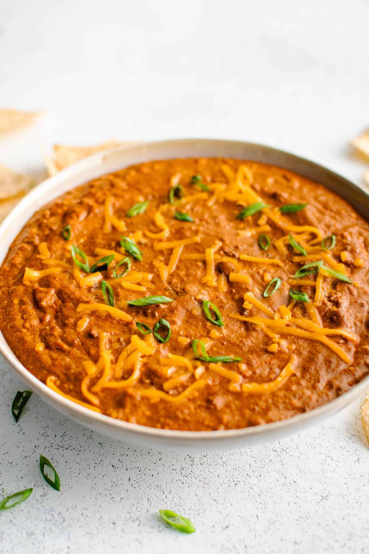 chili cheese dip in a serving bowl garnished with green onions