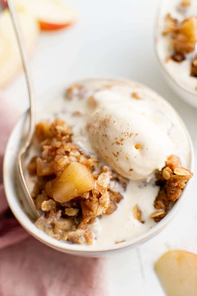 apple crisp made in the crockpot in a bowl with ice cream