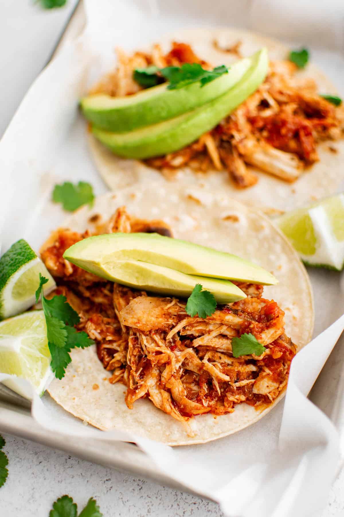 chicken tinga on a tortilla with avocado and lime