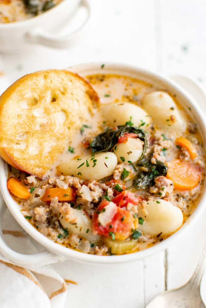 sausage gnocchi soup with bread in a bowl