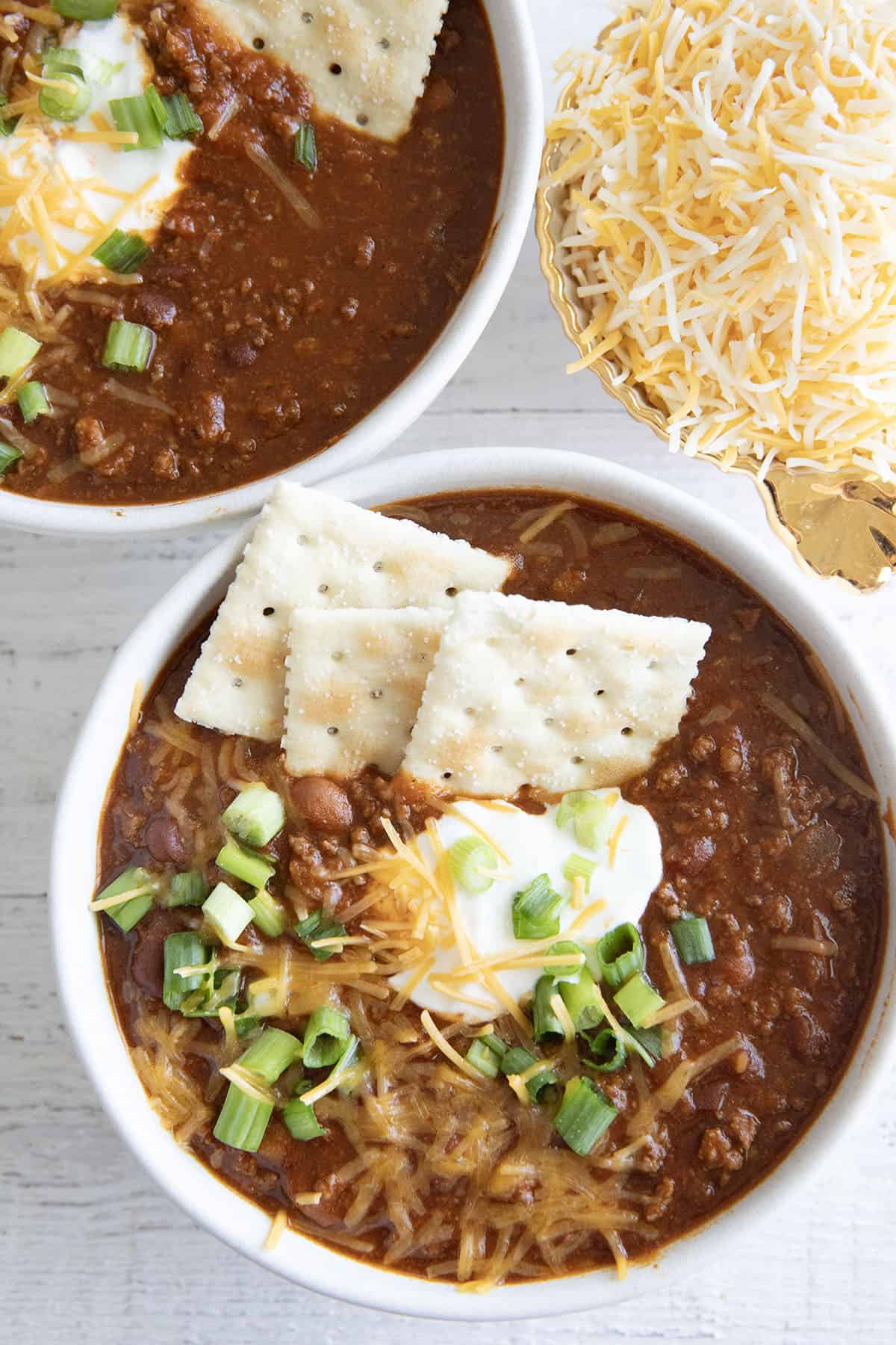 chili in a white bowl with crackers and cheese