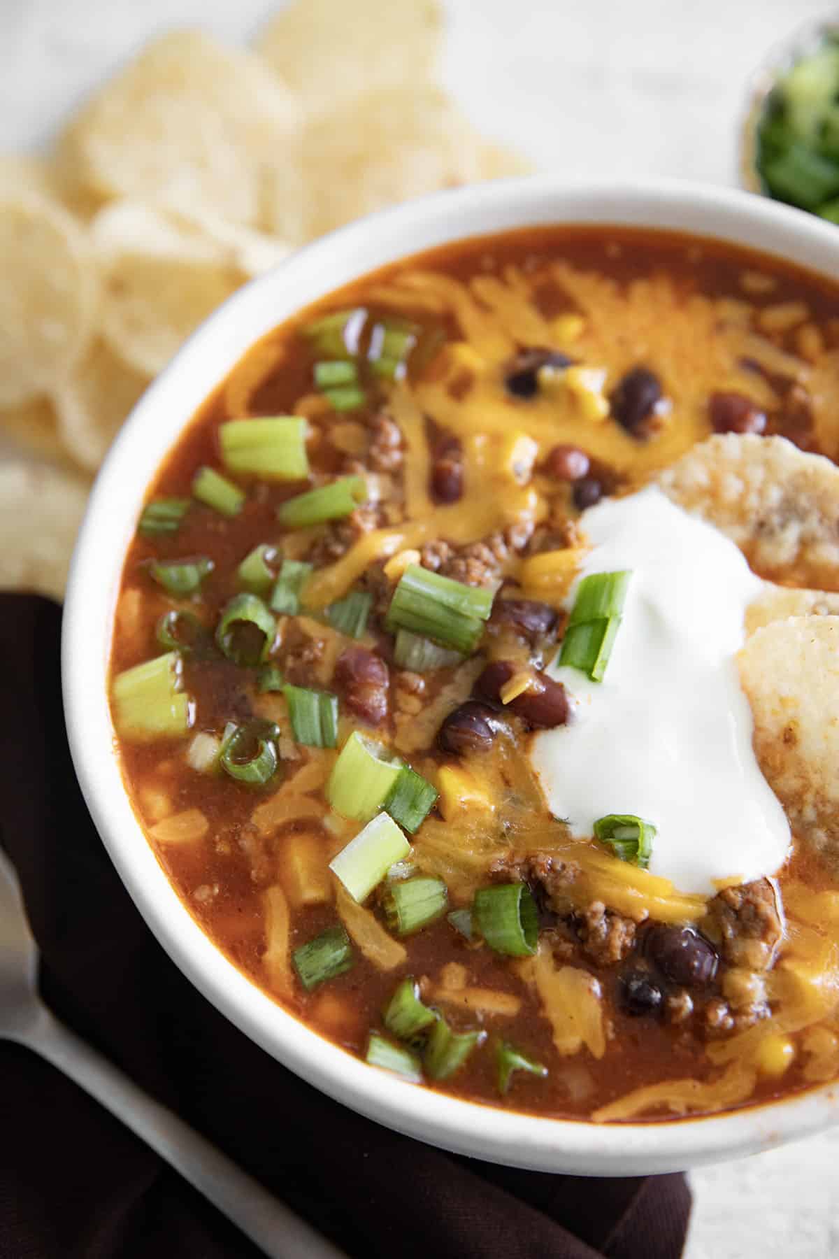 photo of taco soup with sour cream chips and green onion