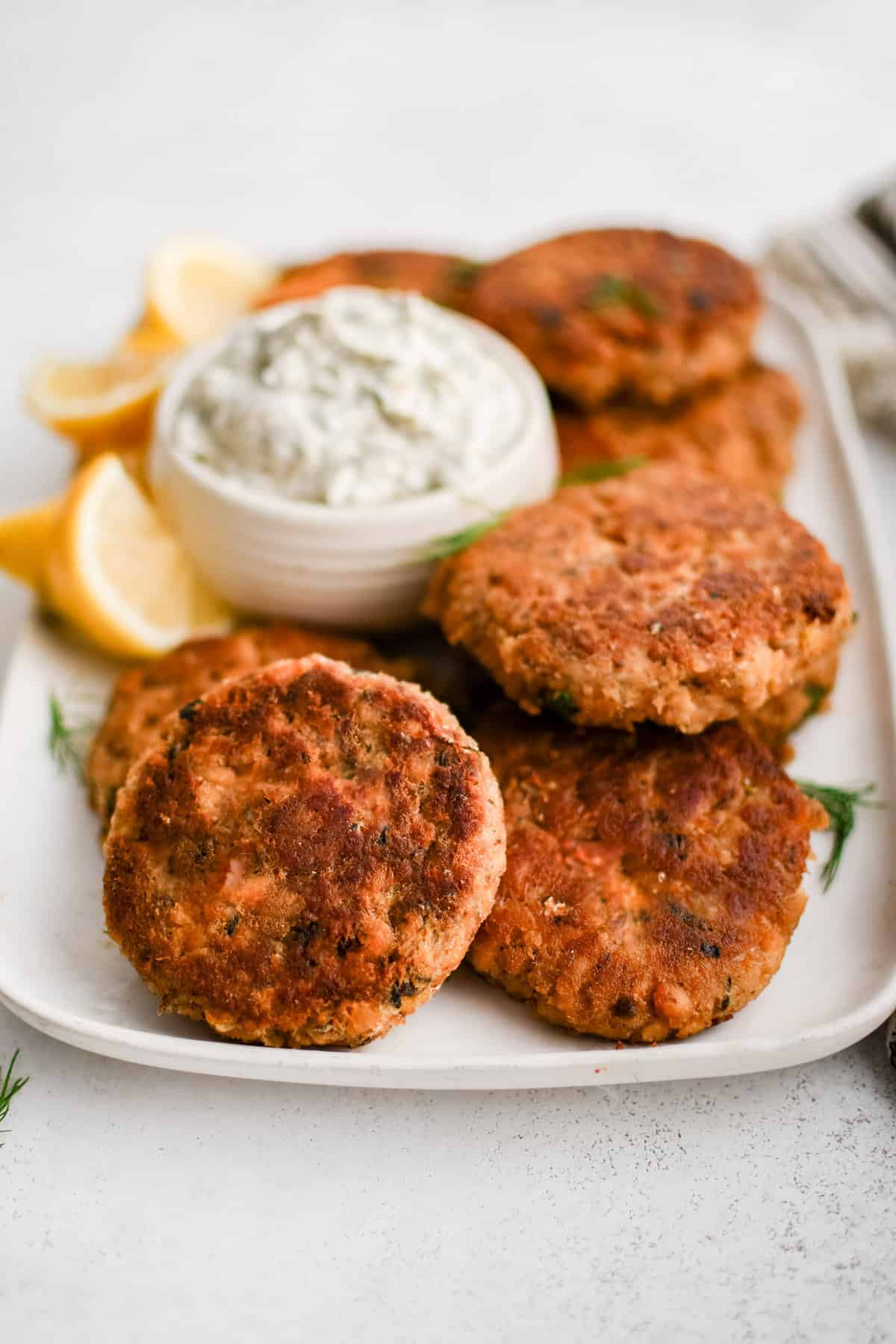 image of prepared salmon patties on a plate with lemon garnish and dill dip