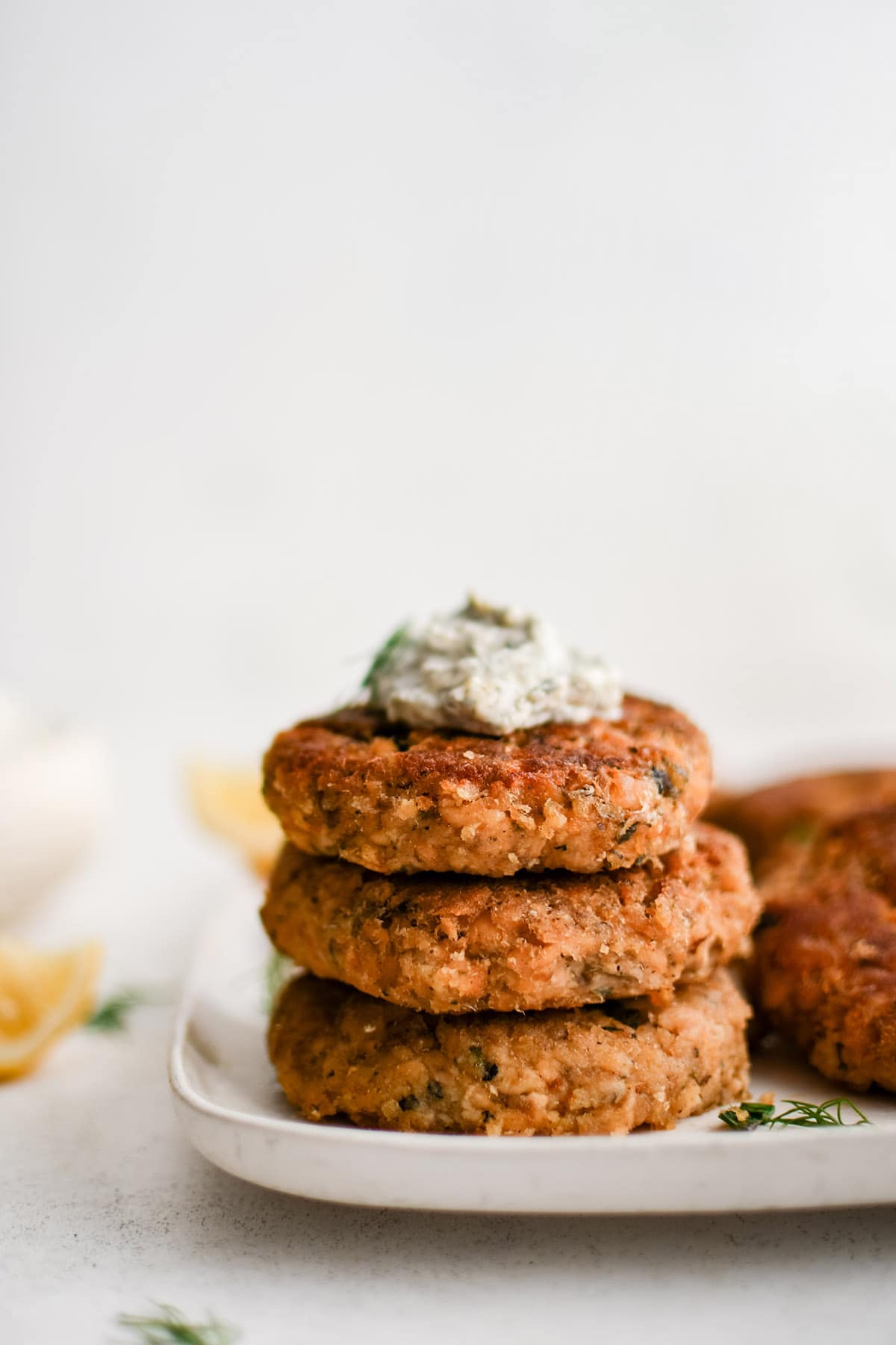 image of stacked salmon patties with dill dip on top of them