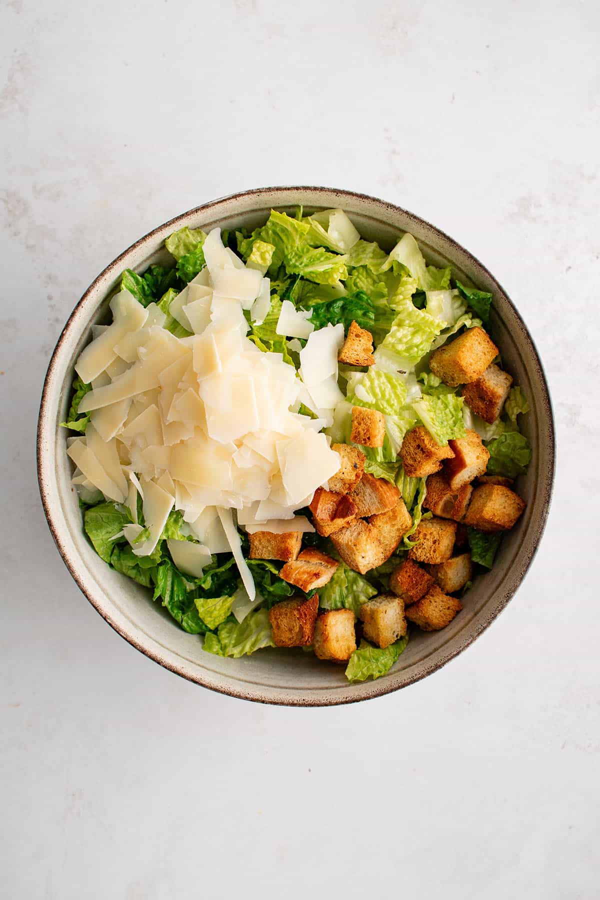 romaine lettuce, croutons, and parmesan cheese in a bowl