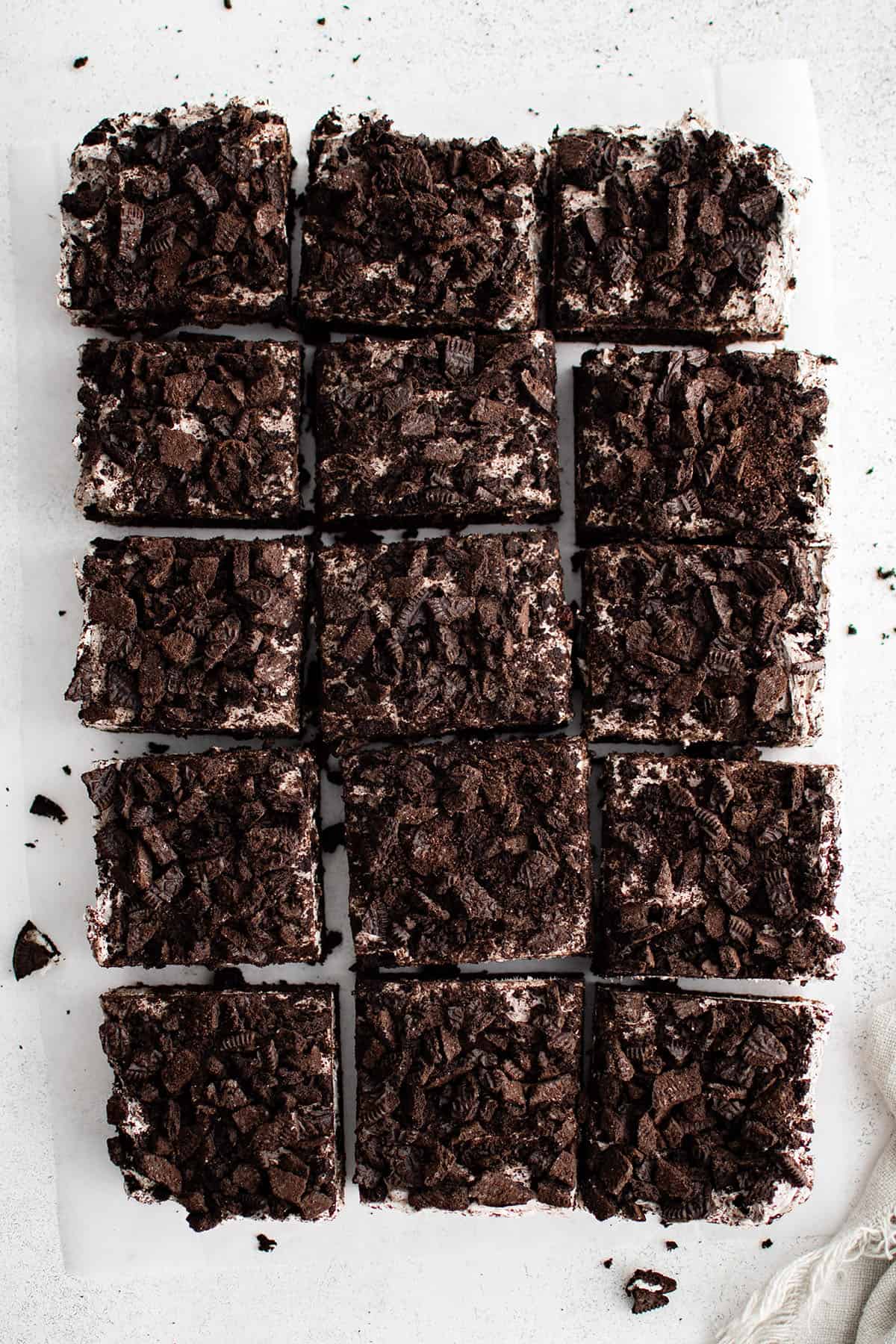 oreo cheesecake bars made with a brownie crust on a white background