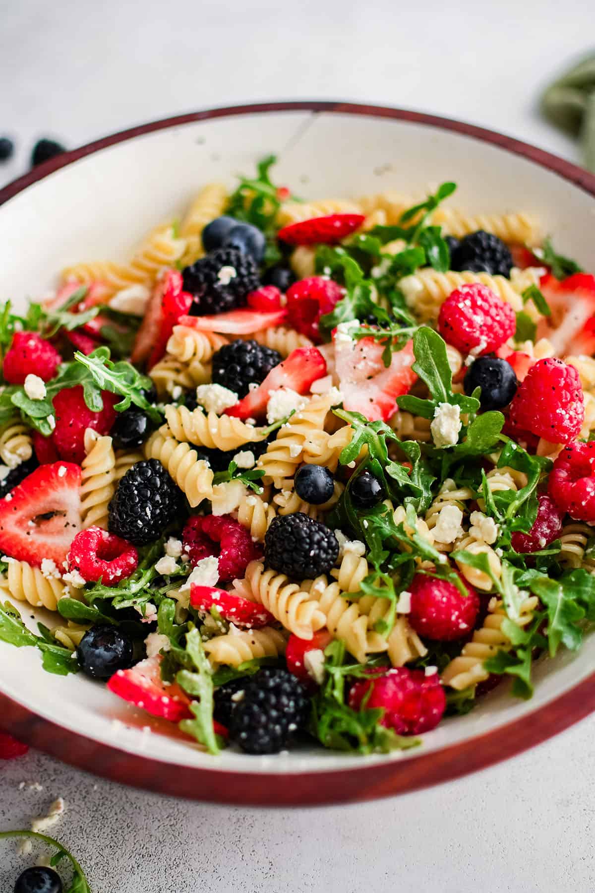 pasta salad with berries and arugula in a large bowl