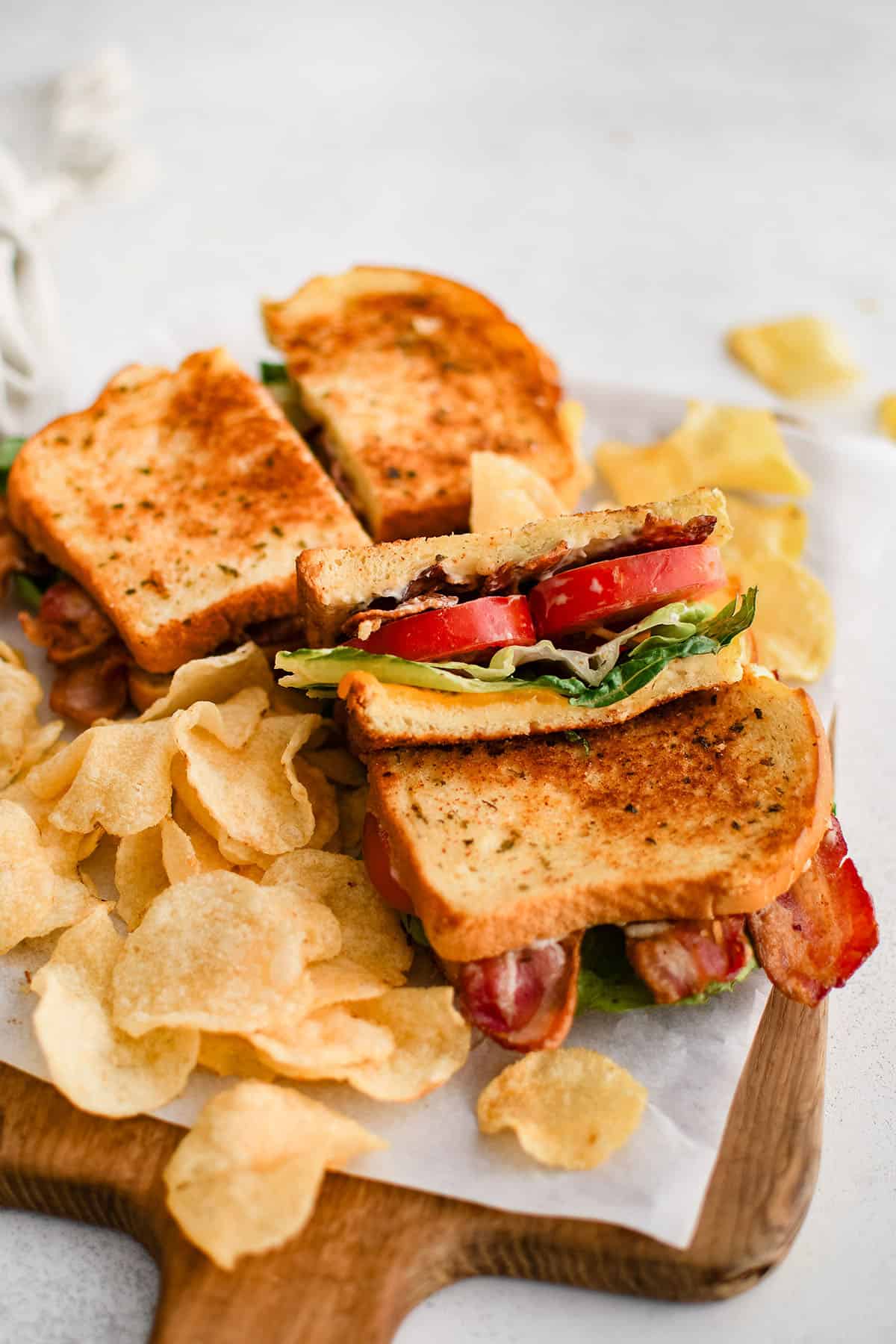 two blt sandwiches on a plate with chips
