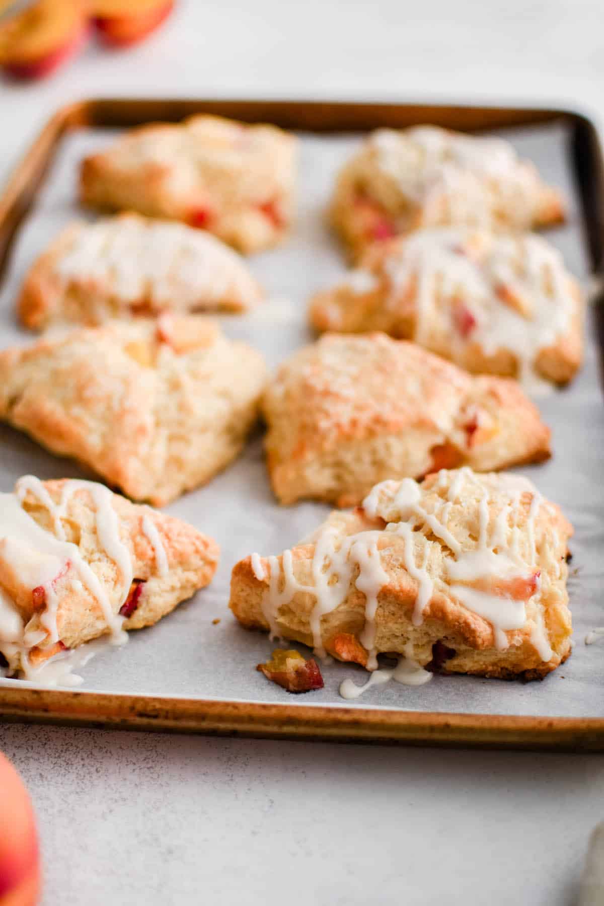 prepared glazed peach scones on a cookie sheet