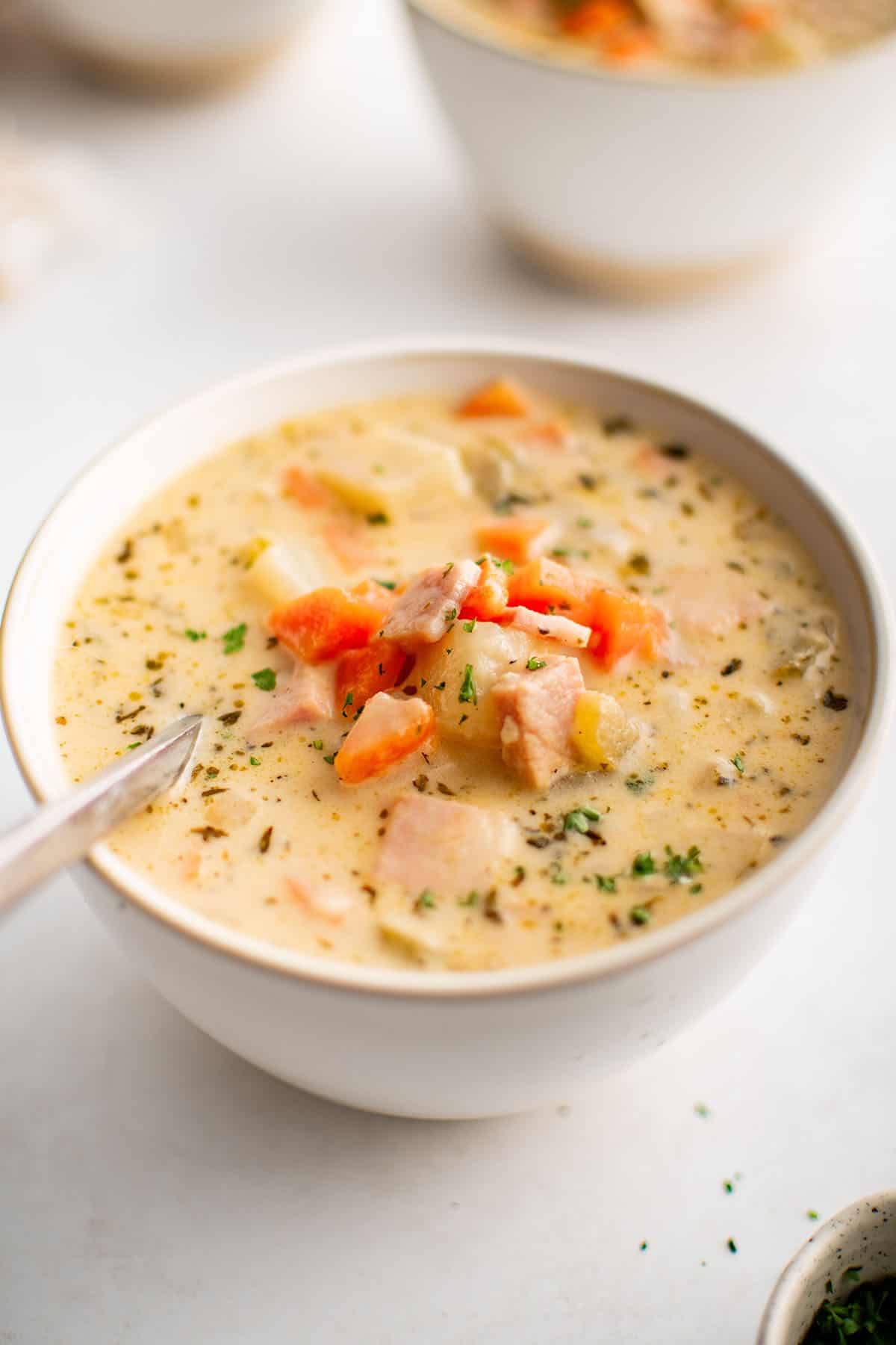 ham and potato soup in a white bowl with a spoon