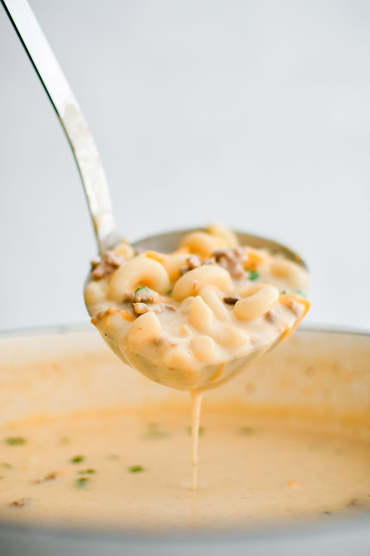 cheesy hamburger noodle soup on a ladle