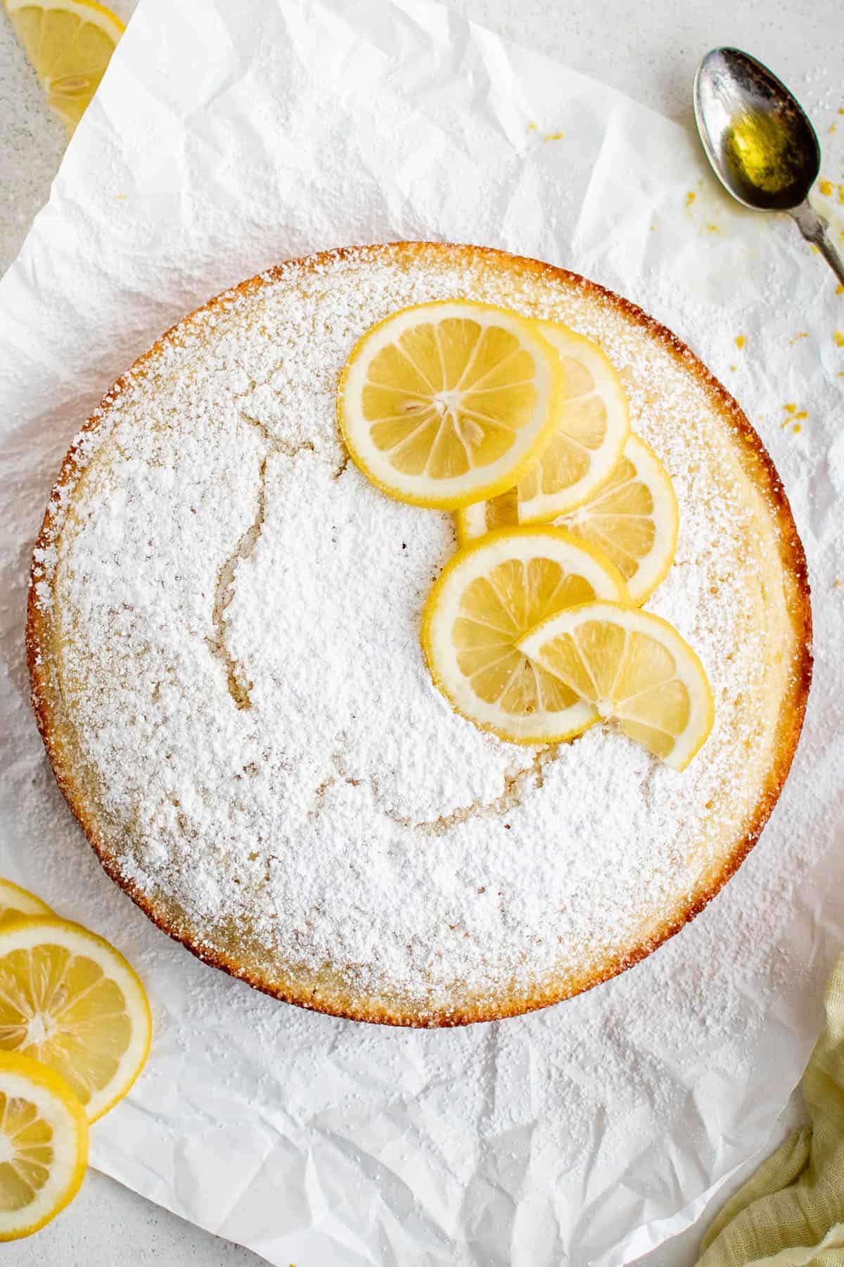 picture of olive oil cake with powdered sugar and slices of lemon