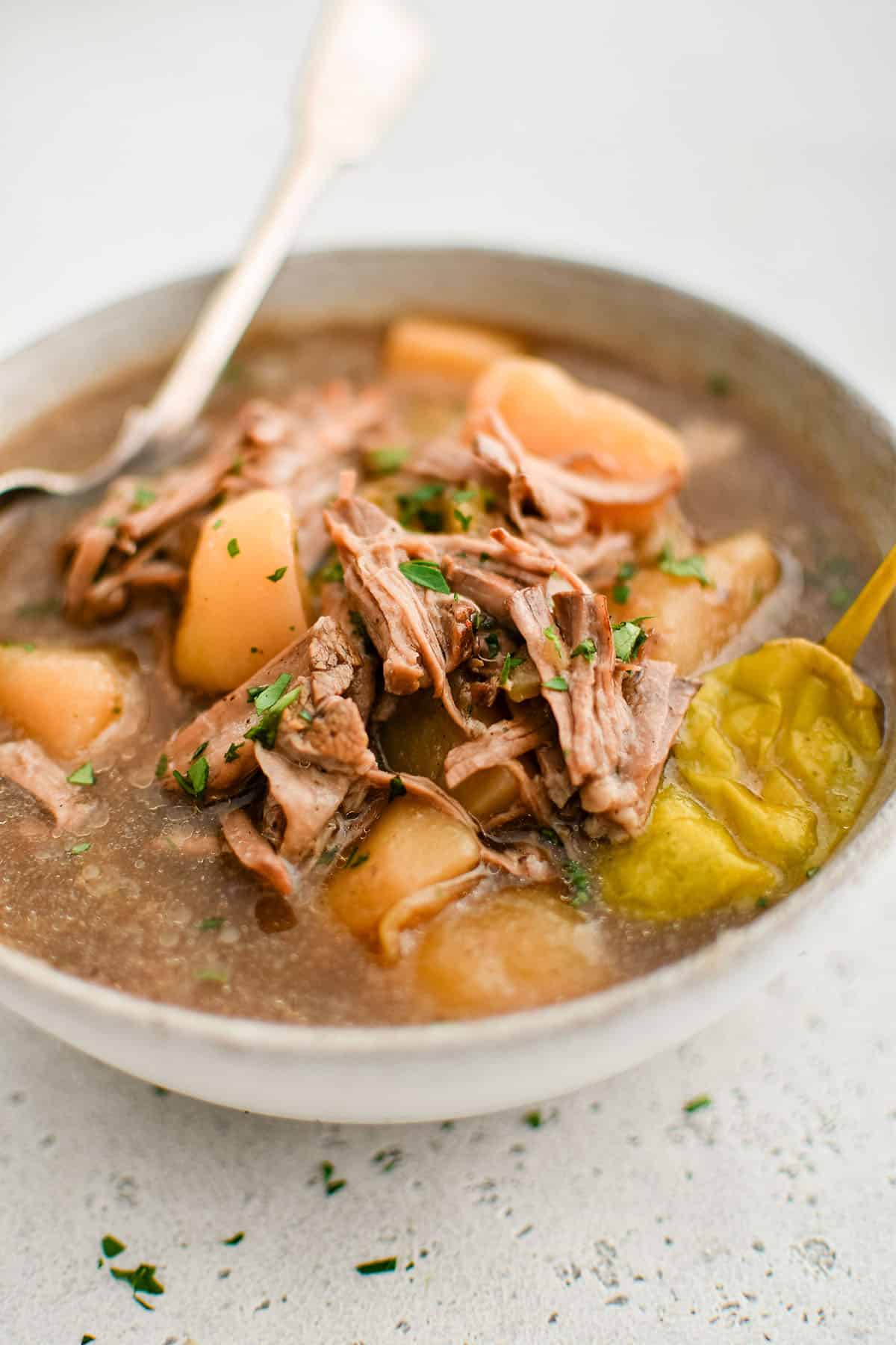 mississippi roast soup with chuck roast and potatoes in a white bowl