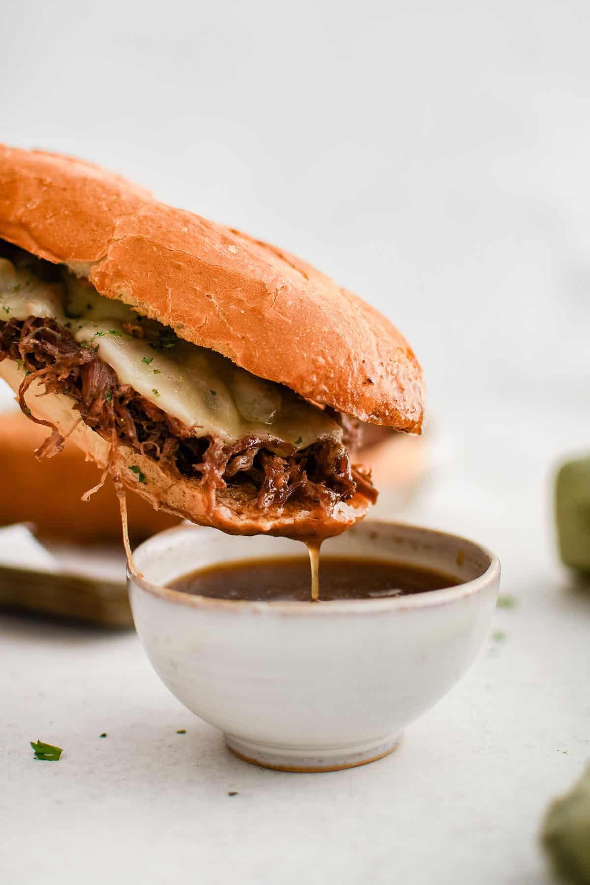 photo of french dip sandwich dipped in au jus