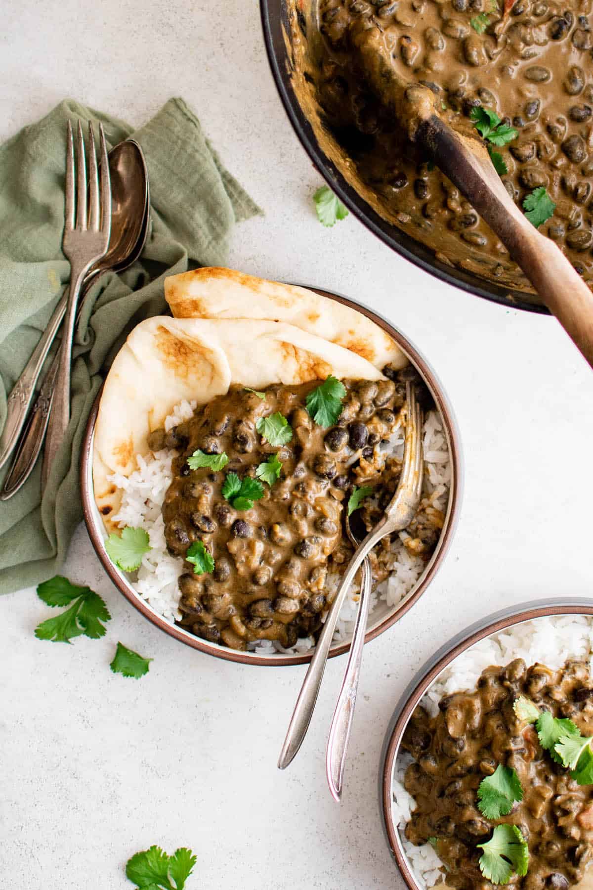 black bean curry in a bowl with naan and white rice