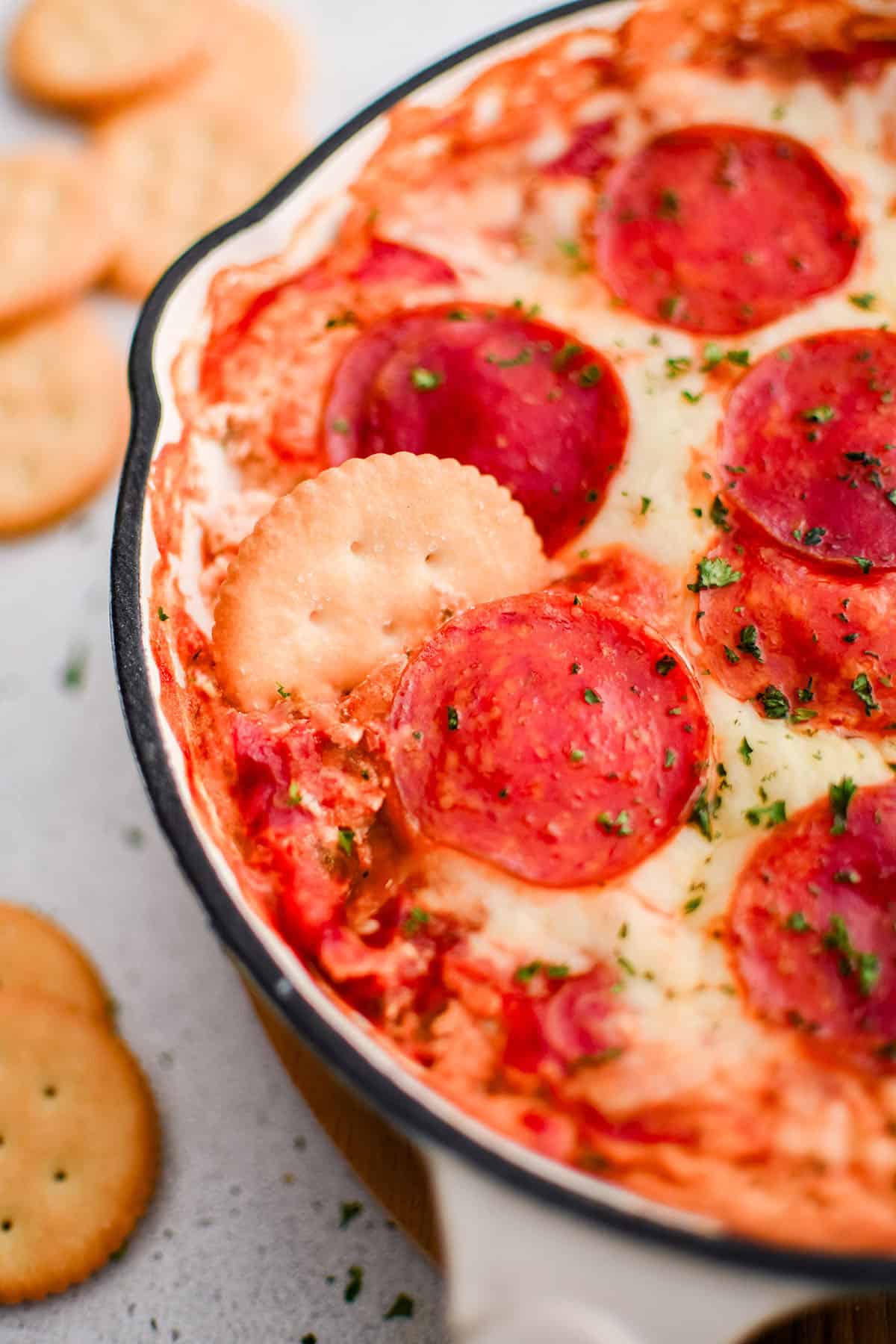 picture of pizza dip in a baking dish with crackers for dipping