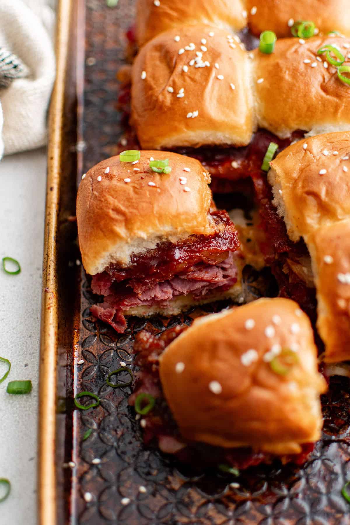 bacon roast beef sliders on a baking sheet