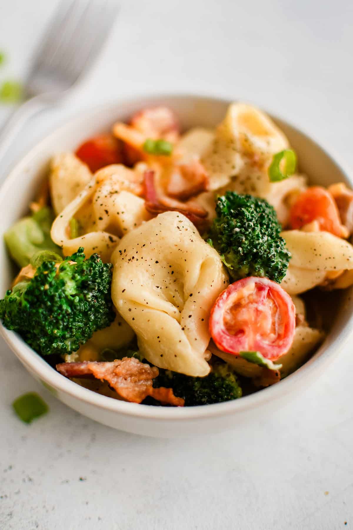 photo of a white bowl with blt tortellini salad
