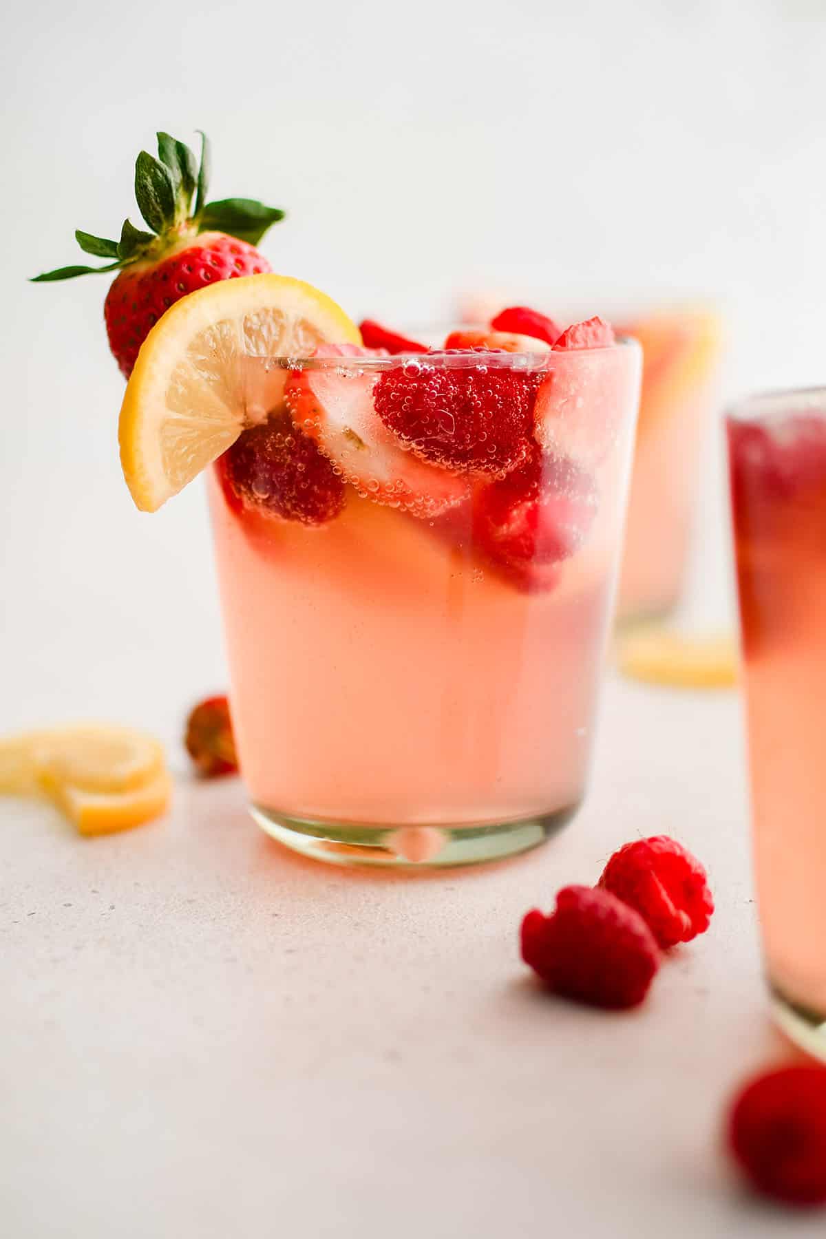 pink lemonade sangria in a glass garnished with lemon, strawberry and raspberry