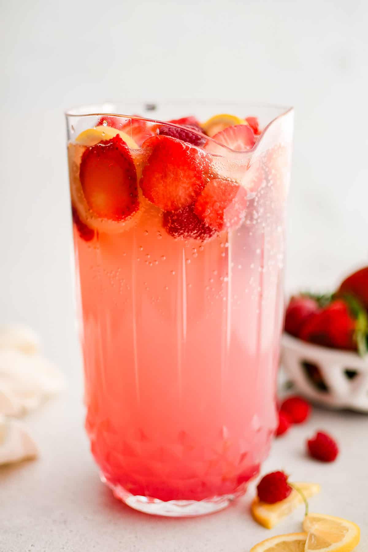 pink lemonade sangria in a pitcher with fresh strawberry, lemon and raspberry at the top