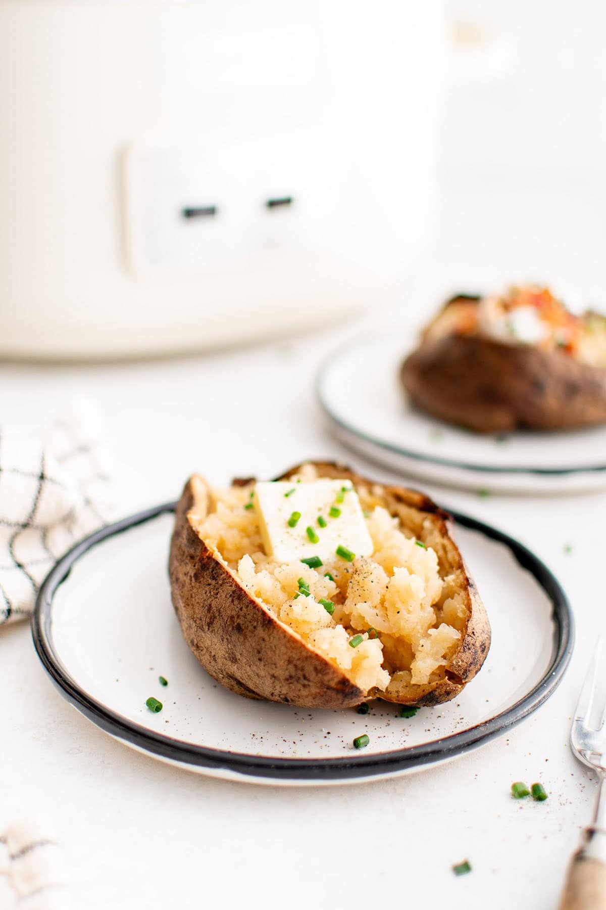 photo of a baked potato with butter on a plate