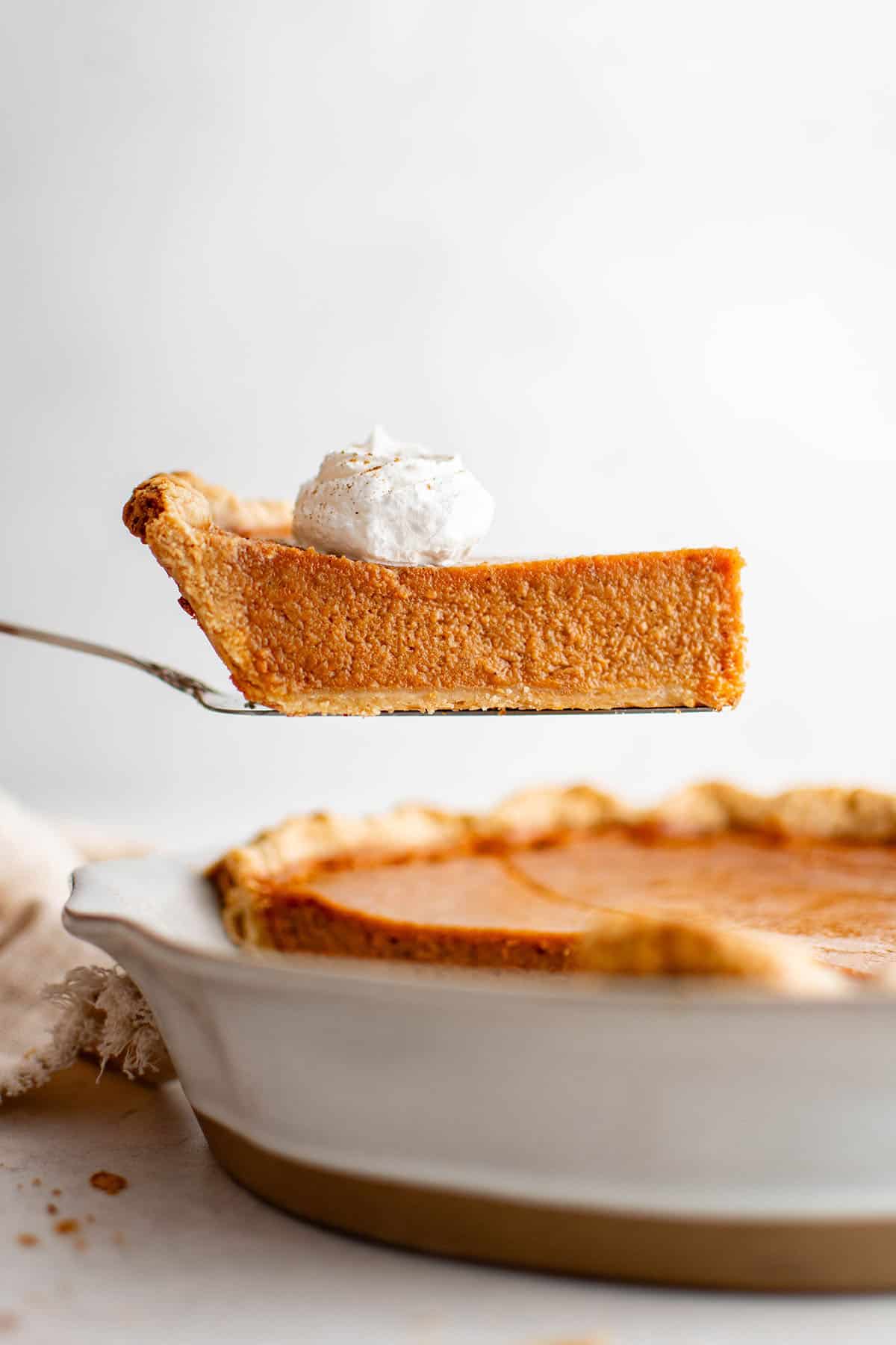 slice of pumpkin pie with a dollop of whipped cream on top of it