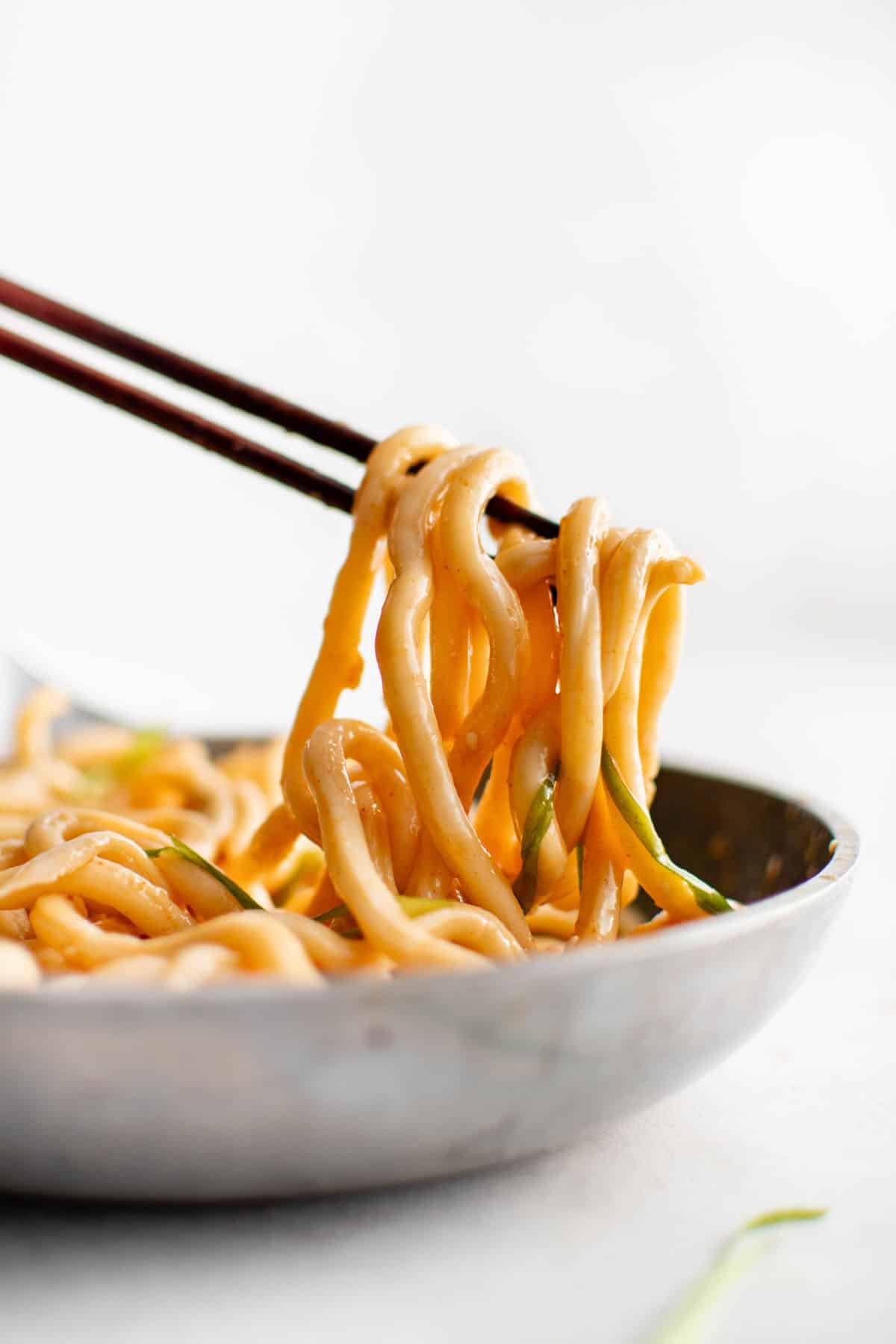 udon noodles being lifted by a pair of chop sticks