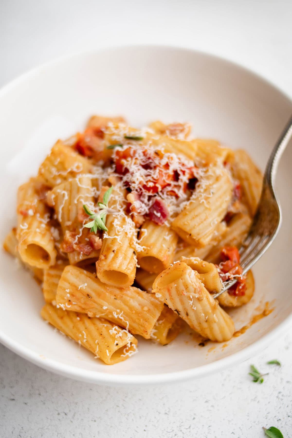 pasta with tomato and bacon in a white bowl