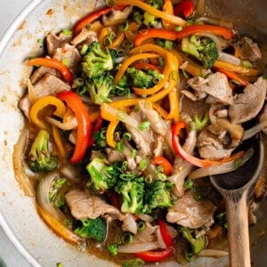 photo of pork stir fry in a pan with a wooden spoon