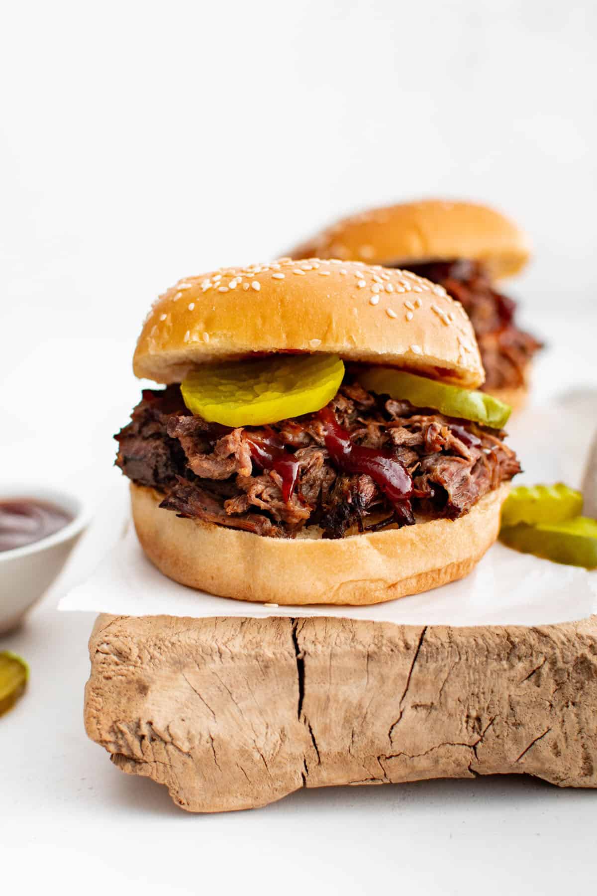 crockpot bbq beef in a sesame bun with pickles and bbq sauce