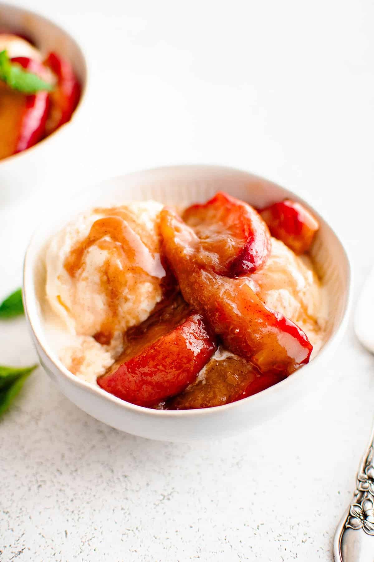 photo of caramelized peaches in a white bowl with ice cream