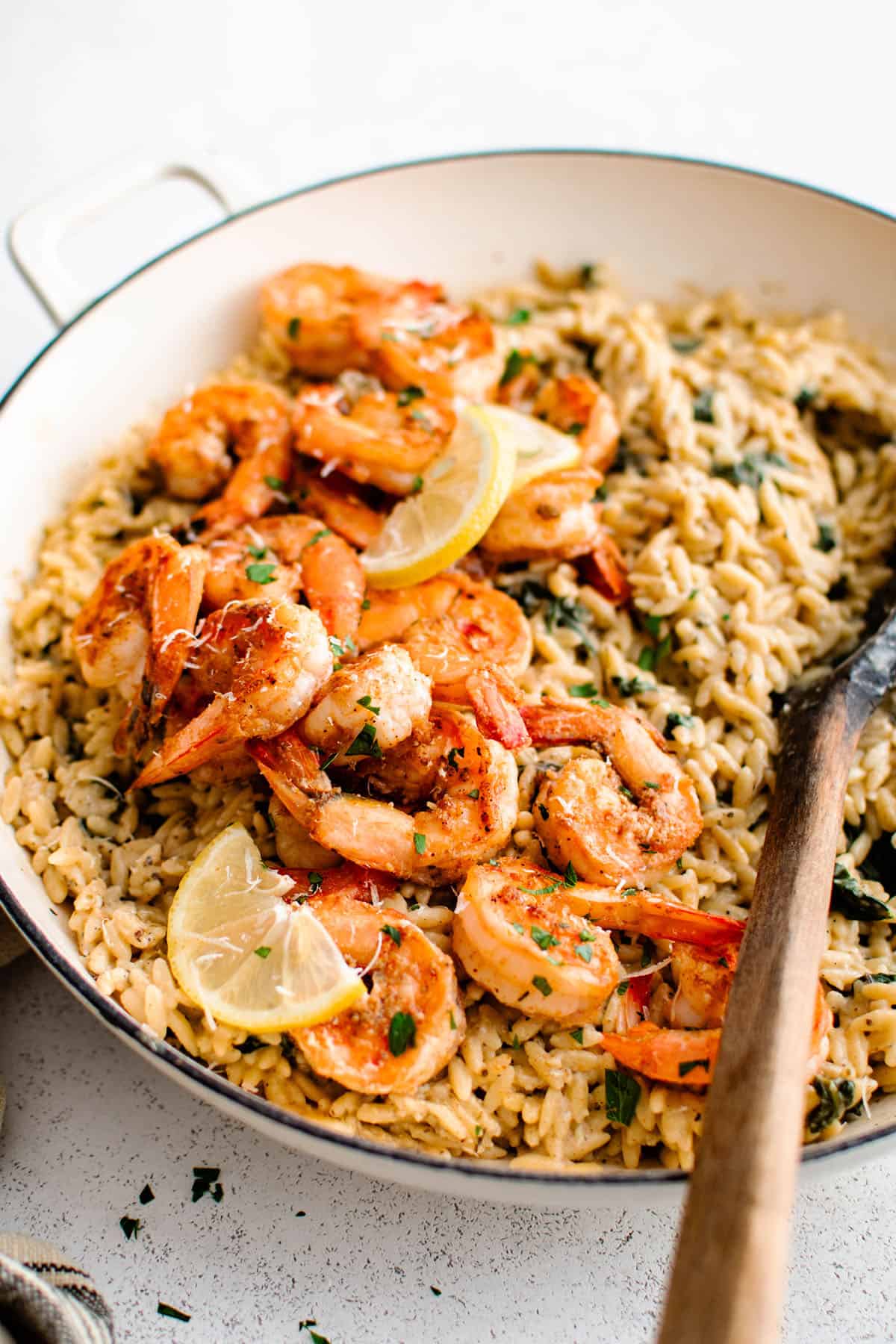 garlic parmesan shrimp orzo in a skillet with a wooden spoon