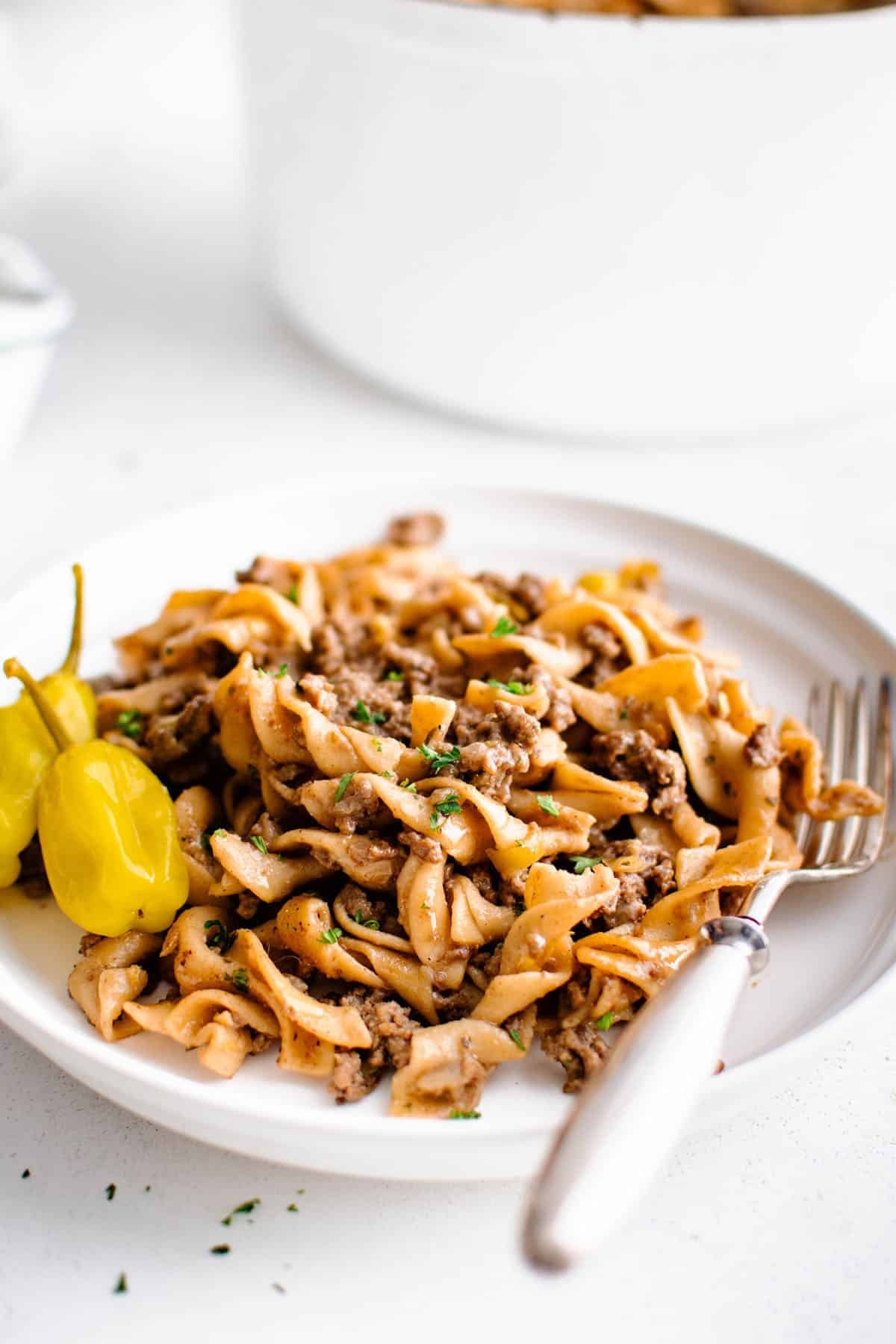 One Pot Mississippi Beef and Noodles on a plate with pepperoncini peppers and a fork